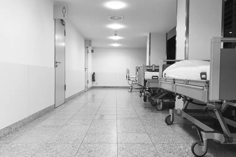 A hospital corridor with beds along the right-hand wall